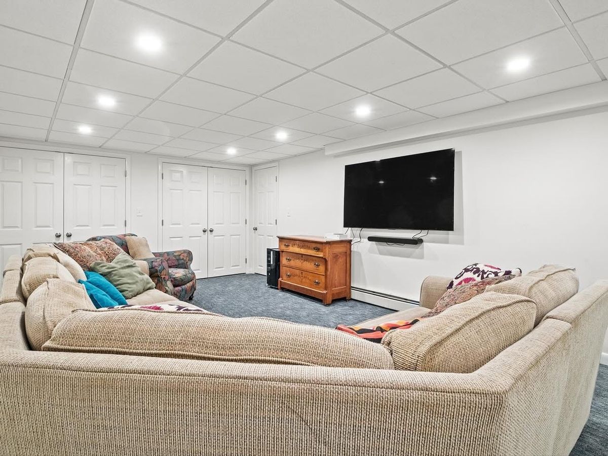 Finished media room with wall-mounted TV, sectional and new carpet
