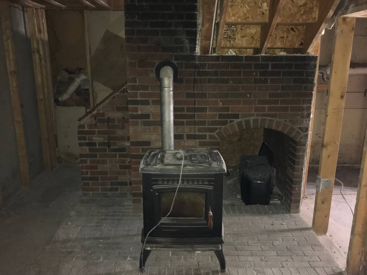 Living area gutted to the framing after a house fire, smoke staining visible on the brick chimney