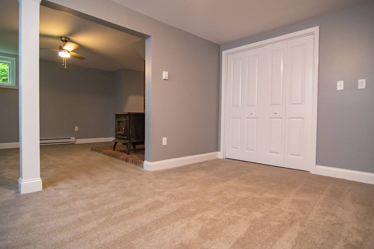 Finished lower level with new carpet, closets and the restored woodstove beyond
