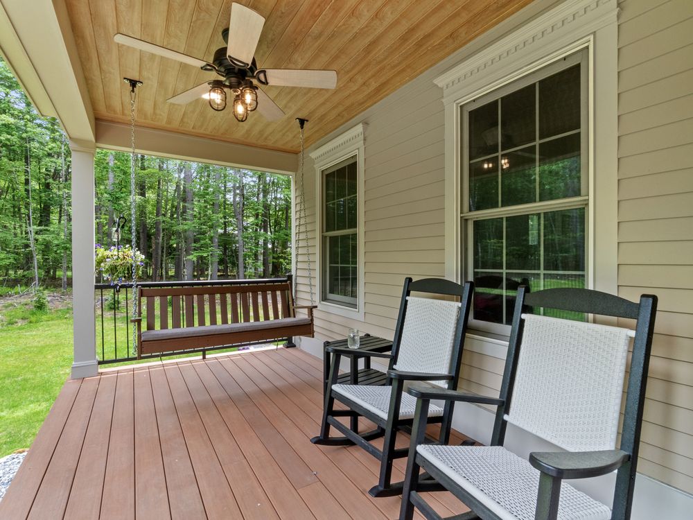 Covered porch with rocking chairs and hanging bench under a beadboard ceiling